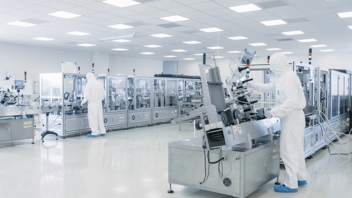 Modern production facility with two employees in cleanroom suits